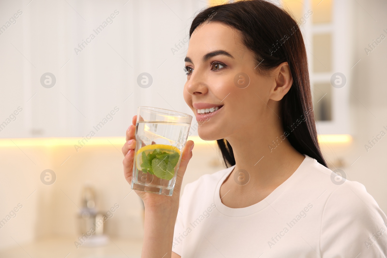 Photo of Young woman with glass of fresh lemonade at home