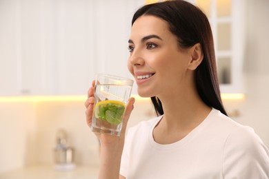 Young woman with glass of fresh lemonade at home