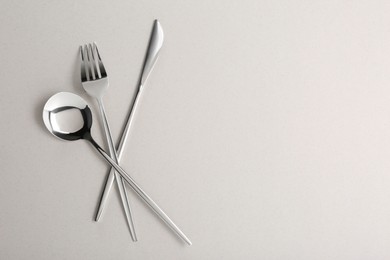 Photo of Spoon, fork and knife on light grey background, flat lay. Space for text