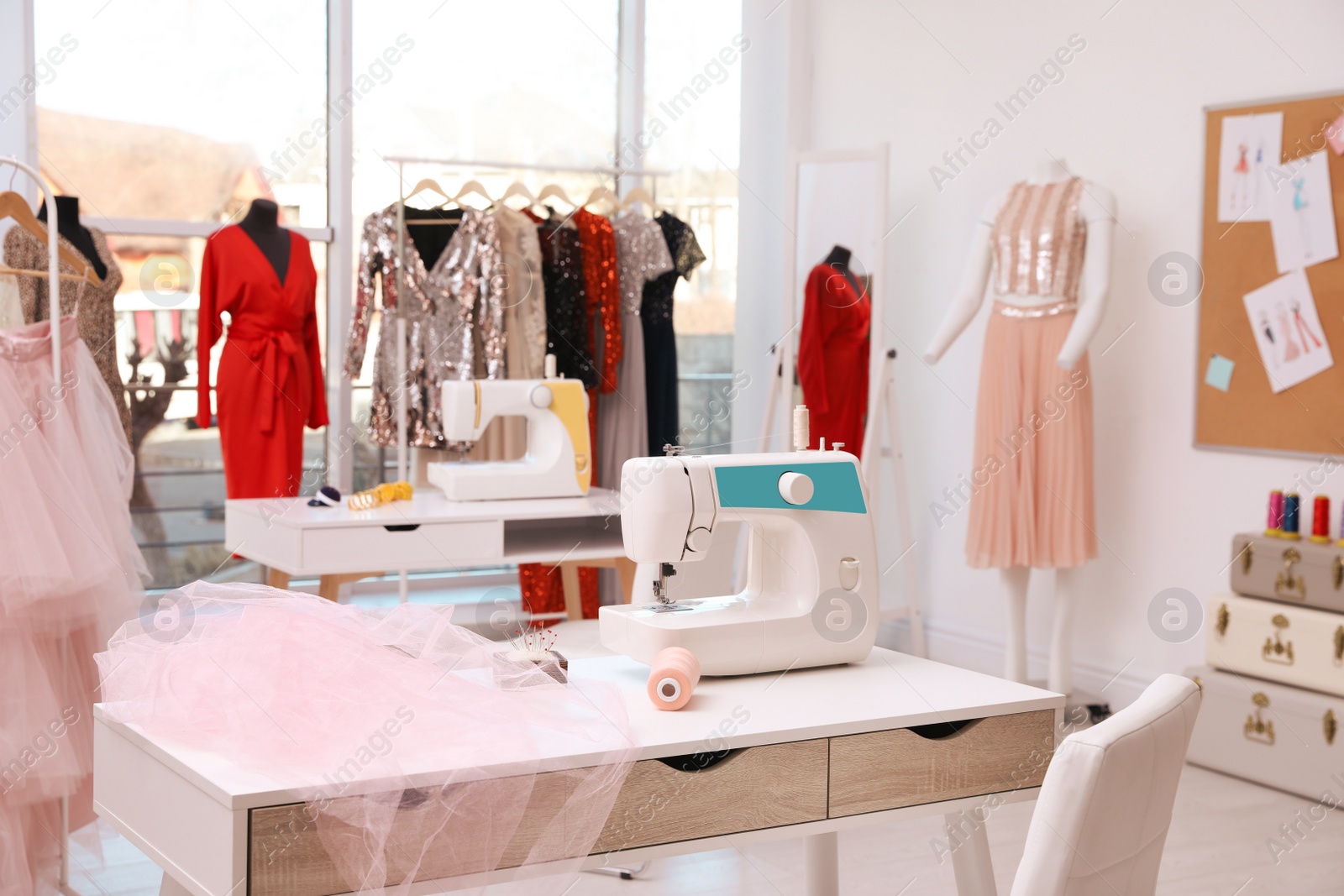 Photo of Sewing machine, thread and fabric on table in dressmaking workshop