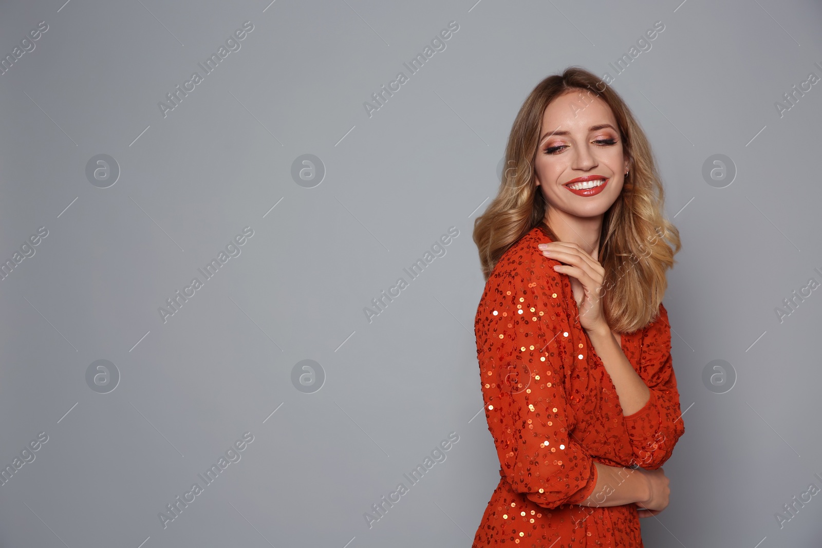 Photo of Happy woman in shiny dress on grey background, space for text. Christmas party