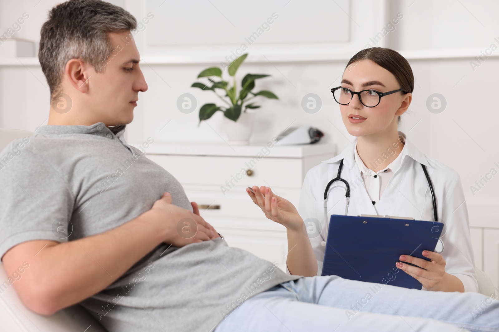 Photo of Gastroenterologist with clipboard consulting patient in clinic