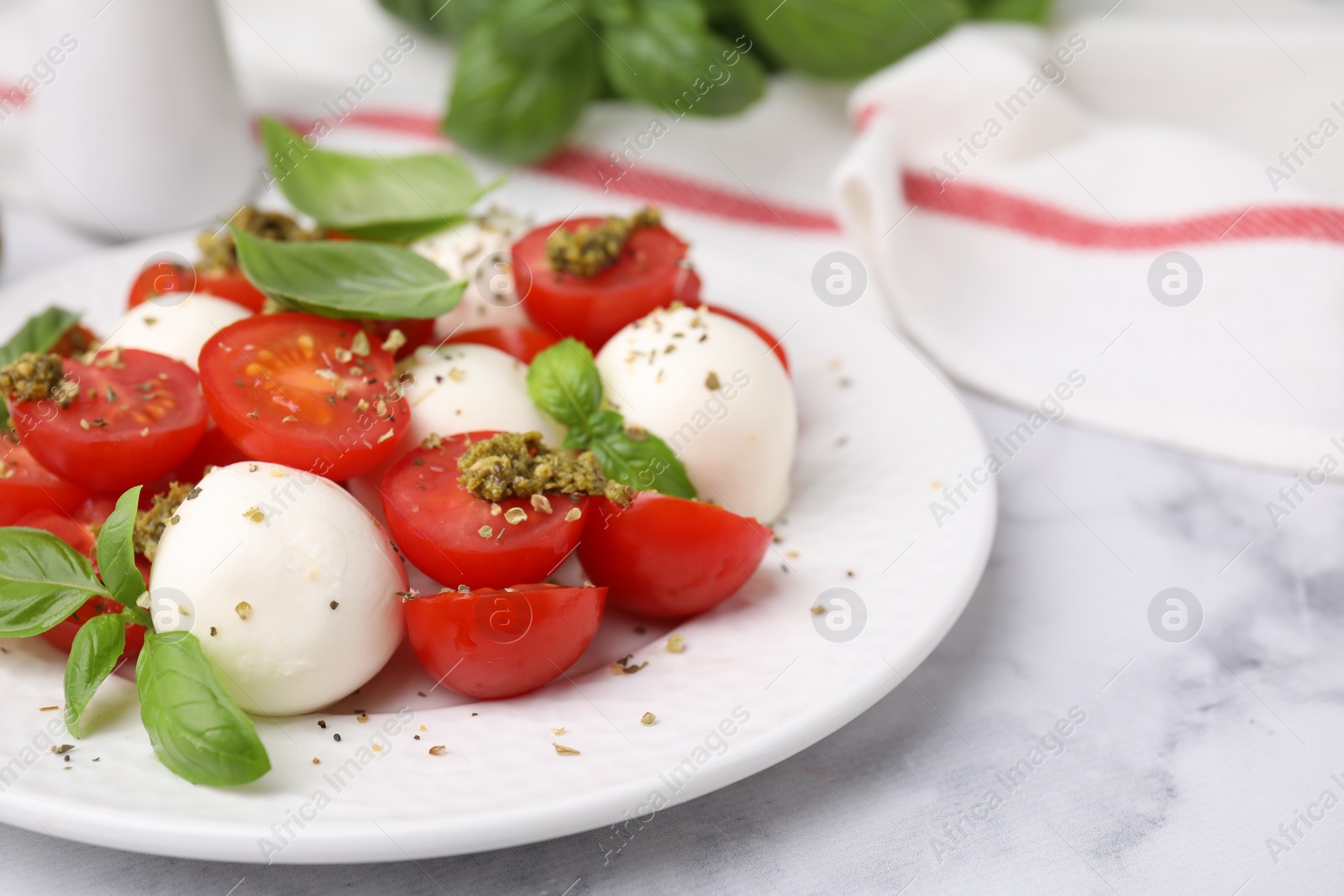 Photo of Tasty salad Caprese with tomatoes, mozzarella balls and basil on white marble table, closeup. Space for text