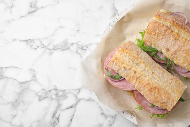 Photo of Tasty sandwiches with ham on white marble table, top view. Space for text