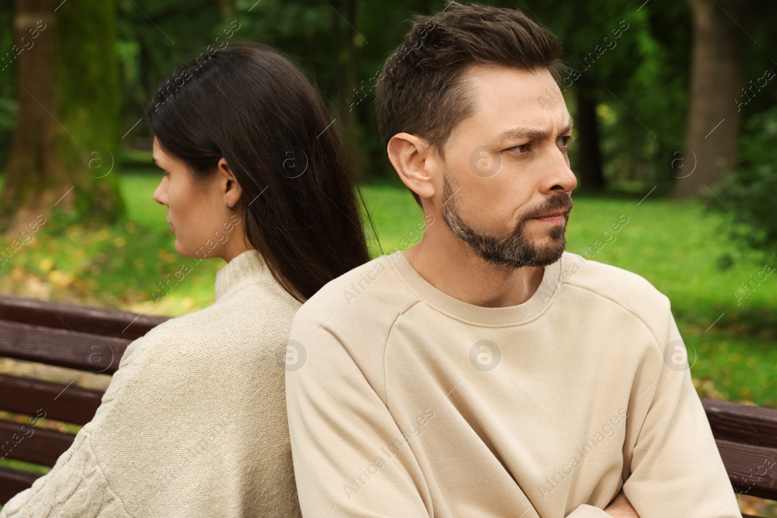 Photo of Upset arguing couple sitting on bench in park. Relationship problems