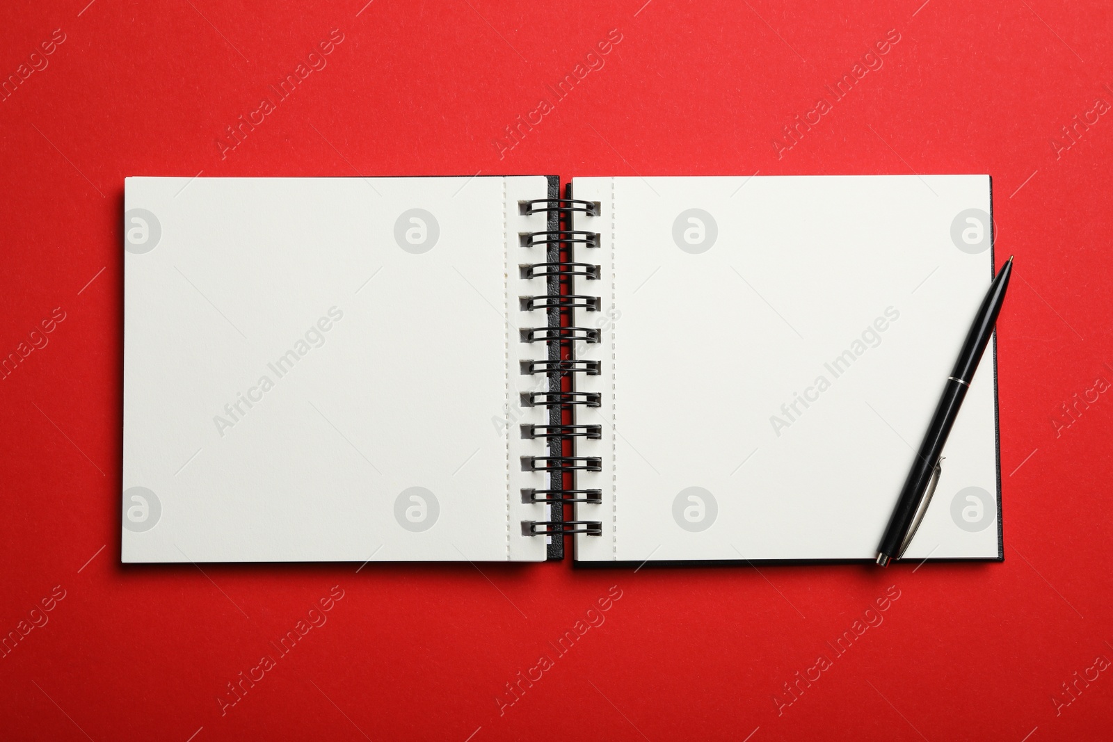 Photo of Stylish open notebook and pen on red background, top view