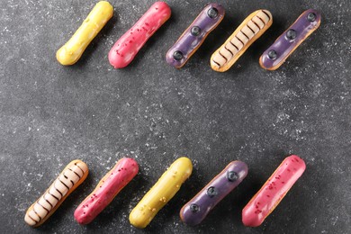 Photo of Different tasty glazed eclairs on dark textured table, flat lay. Space for text