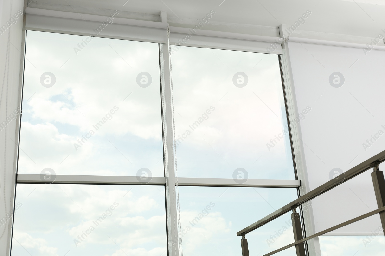 Photo of Large window with open roller blinds indoors