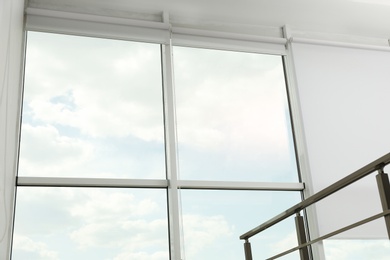 Photo of Large window with open roller blinds indoors