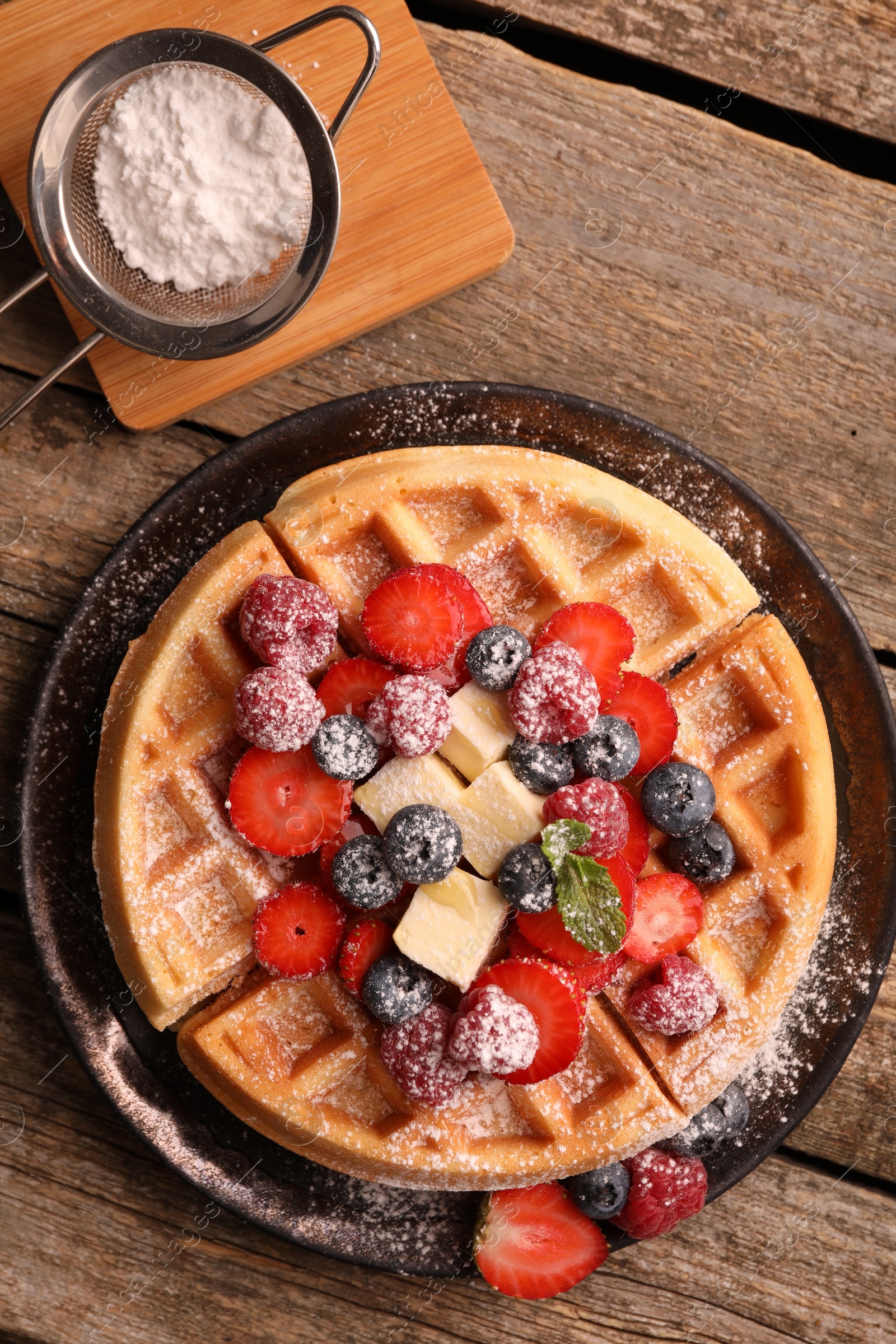 Photo of Tasty Belgian waffle with fresh berries, cheese and powdered sugar on wooden table, flat lay