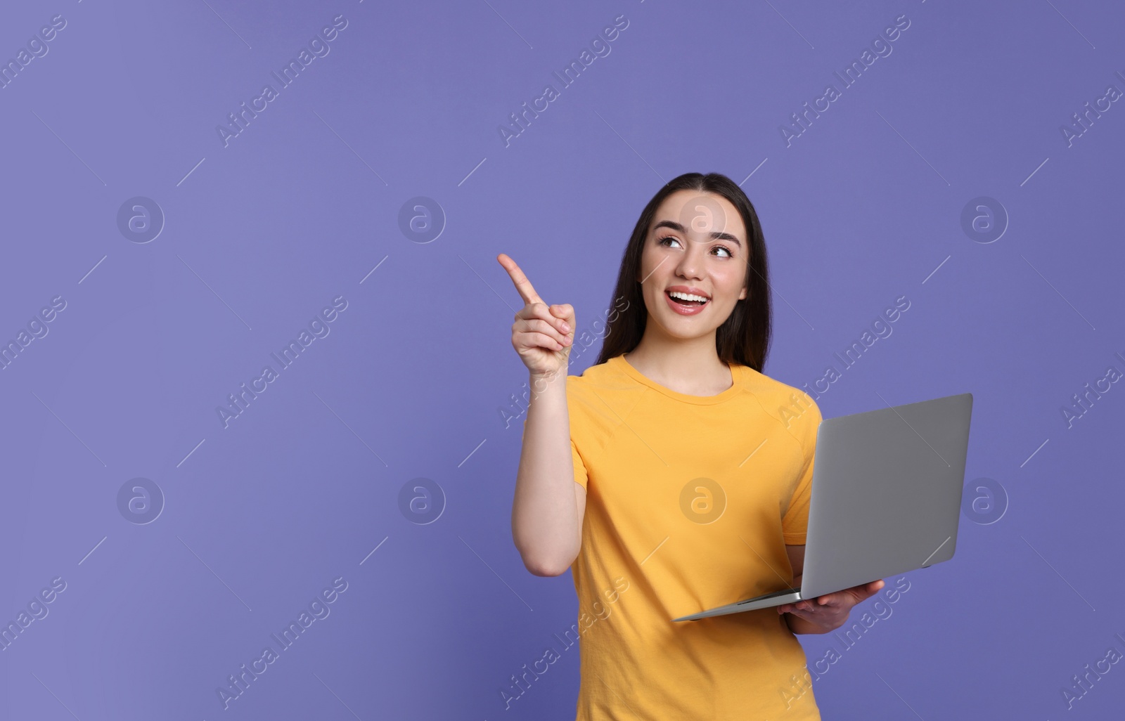 Photo of Smiling young woman with laptop on lilac background, space for text