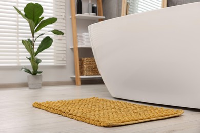 Photo of Soft yellow bath mat on floor in bathroom