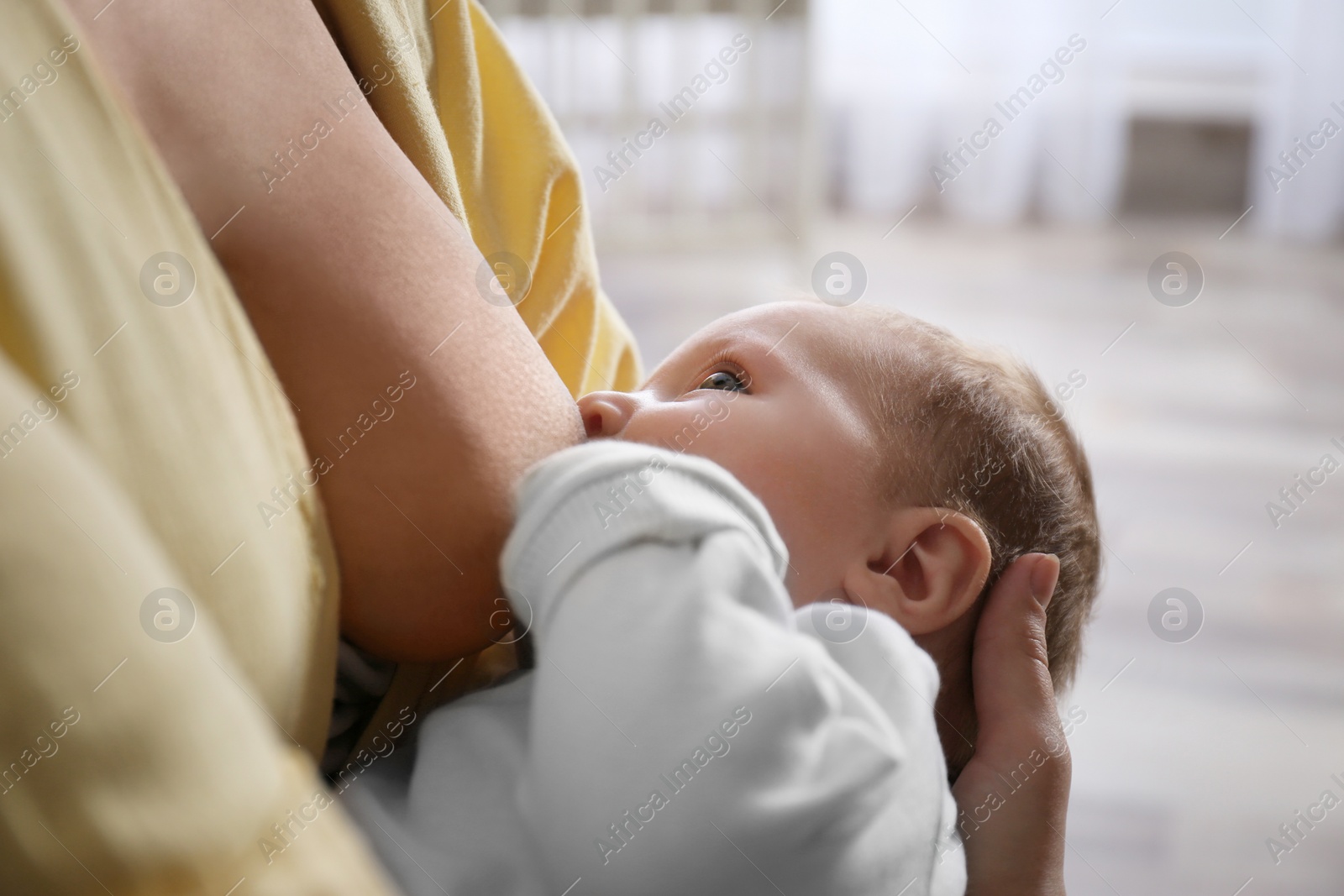 Photo of Young woman breast feeding her little baby at home, closeup