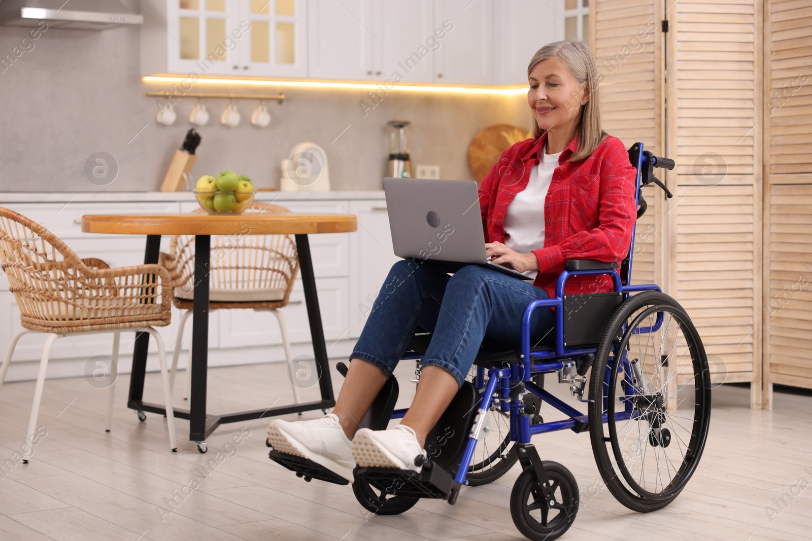 Photo of Woman in wheelchair using laptop at home