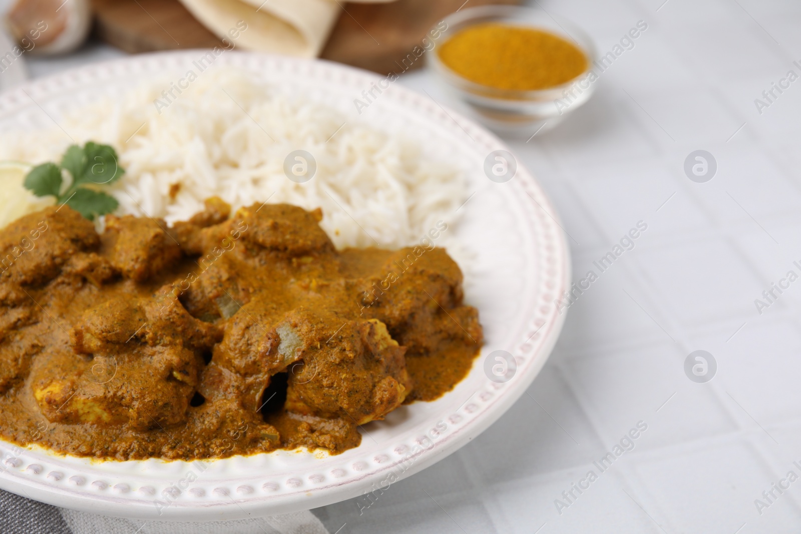 Photo of Delicious chicken curry with rice on white tiled table, closeup