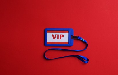 Photo of Plastic vip badge on red background, top view