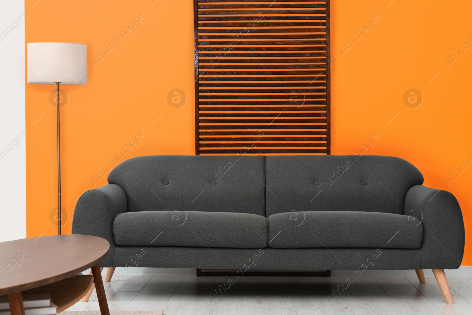 Photo of Stylish room with cosy sofa near orange wall. Interior design