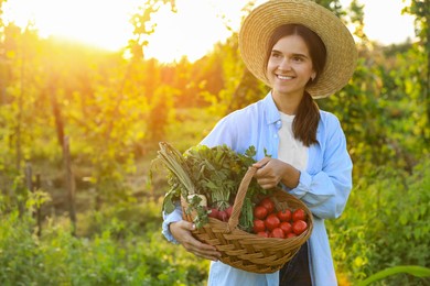 Photo of Woman with basketdifferent fresh ripe vegetables on farm. Space for text