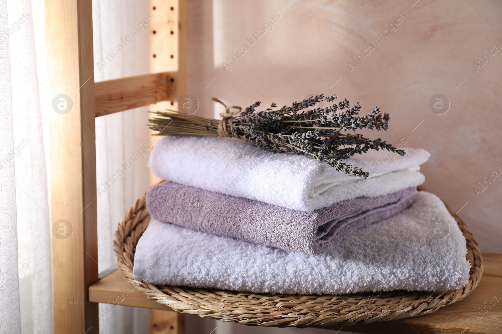Photo of Stacked soft towels and lavender on wooden shelf indoors
