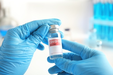 Photo of Doctor holding vial with vaccine against Covid-19 indoors, closeup