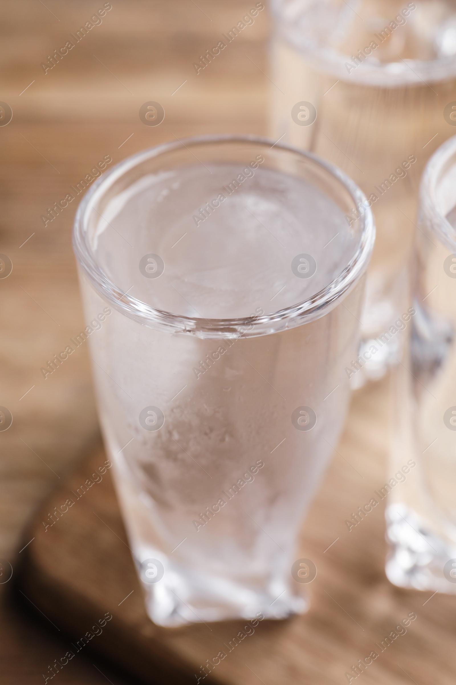 Photo of Vodka in shot glasses on wooden table, closeup