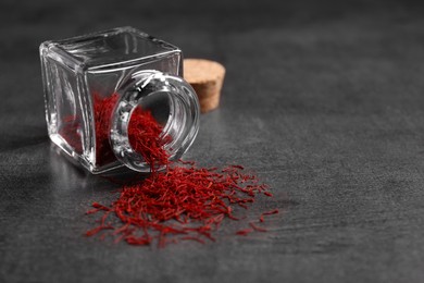 Photo of Aromatic saffron and glass jar on gray table, space for text