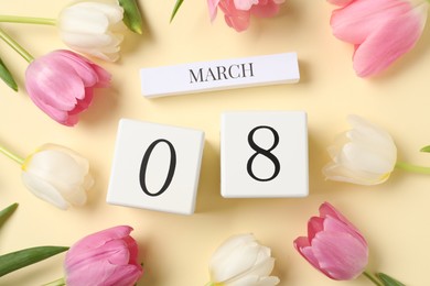 International Women's day - 8th of March. Wooden block calendar and beautiful flowers on beige background, flat lay