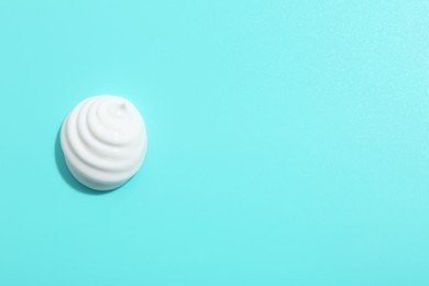 Photo of Drop of face cream on light blue background, top view. Space for text