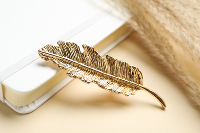 Photo of Stylish hair clip and book on beige background