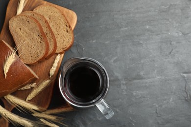 Delicious kvass, bread and spikes on black slate table, flat lay. Space for text