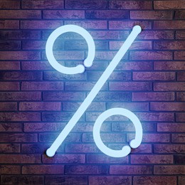 Image of Glowing neon percent sign on brick wall