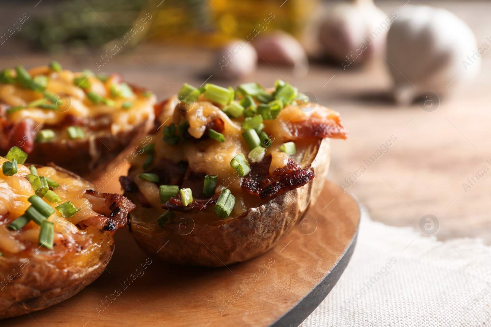 Photo of Board of baked potatoes with cheese and bacon on table, closeup