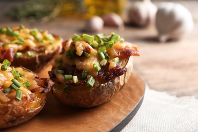 Photo of Board of baked potatoes with cheese and bacon on table, closeup