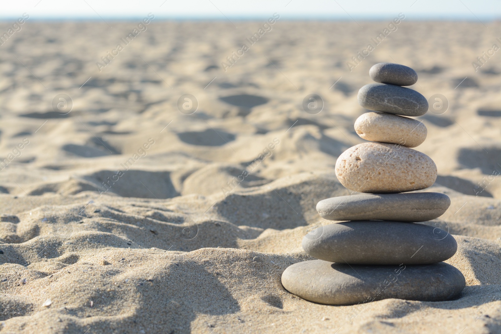 Photo of Stack of stones on sandy beach, space for text