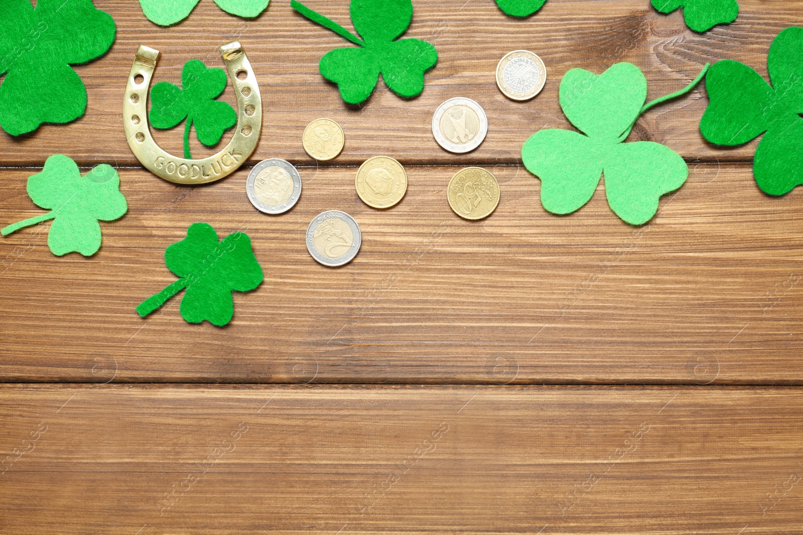 Photo of Flat lay composition with clover leaves and horseshoe on wooden table, space for text. St. Patrick's Day celebration