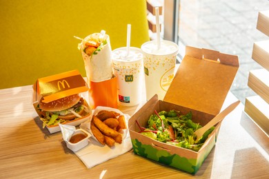 WARSAW, POLAND - SEPTEMBER 16, 2022: Big Mac hamburger, fried potatoes and cold drinks on table in McDonald's cafe