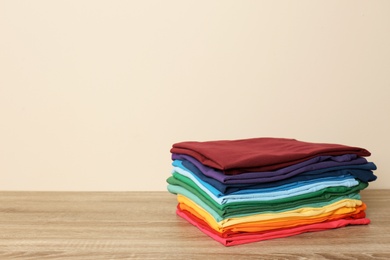 Photo of Stack of bright folded clothes on table against light background. Space for text