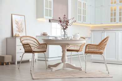 Photo of Dining room interior with tea set on round table and wicker chairs