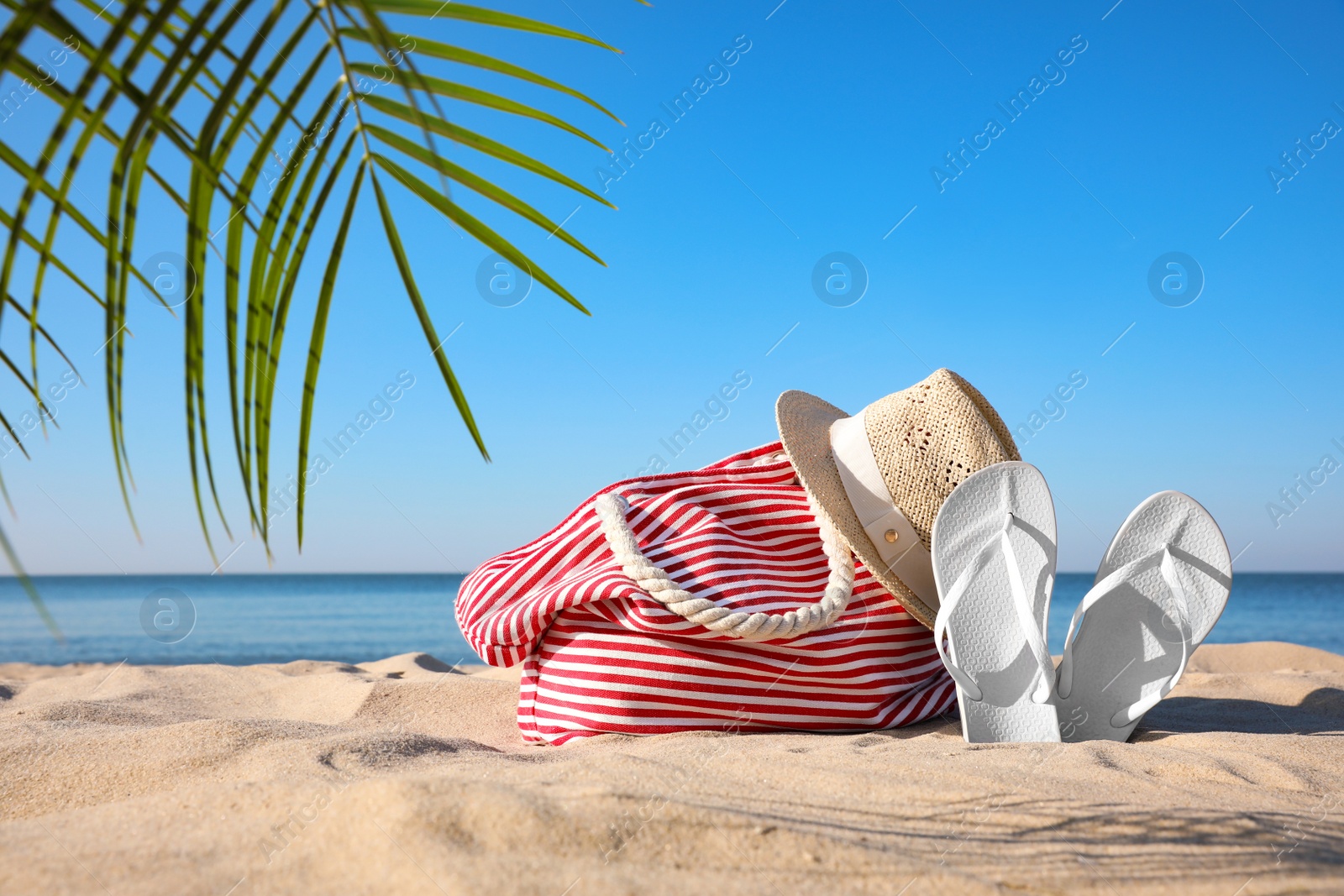 Photo of Set with stylish beach accessories on sand near sea