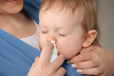 Photo of Mother helping her baby to use nasal spray, closeup