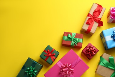 Many colorful gift boxes on yellow background, flat lay. Space for text