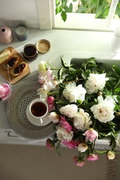 Beautiful peonies and breakfast on kitchen counter, flat lay