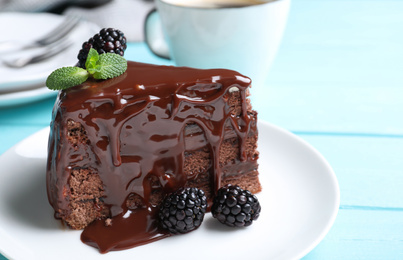 Delicious chocolate cake with blackberries on light blue table, closeup