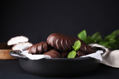 Photo of Delicious chocolate covered marshmallows with mint on black table