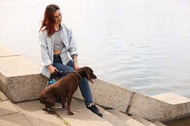 Photo of Woman with her cute German Shorthaired Pointer dog outdoors, space for text