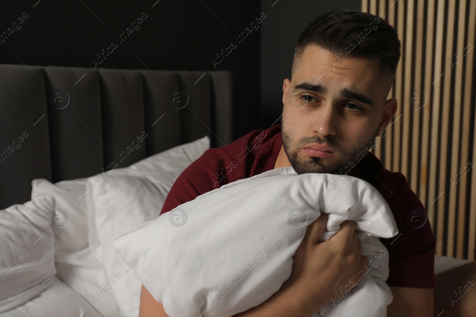 Photo of Sad man hugging pillow on bed at home. Space for text