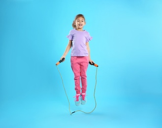 Full length portrait of girl jumping rope on color background
