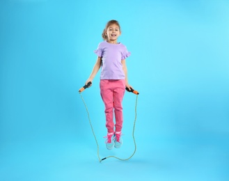 Photo of Full length portrait of girl jumping rope on color background