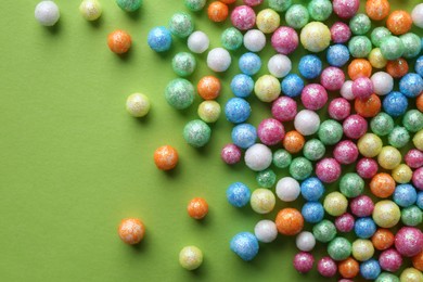 Small colorful beads on green background, flat lay