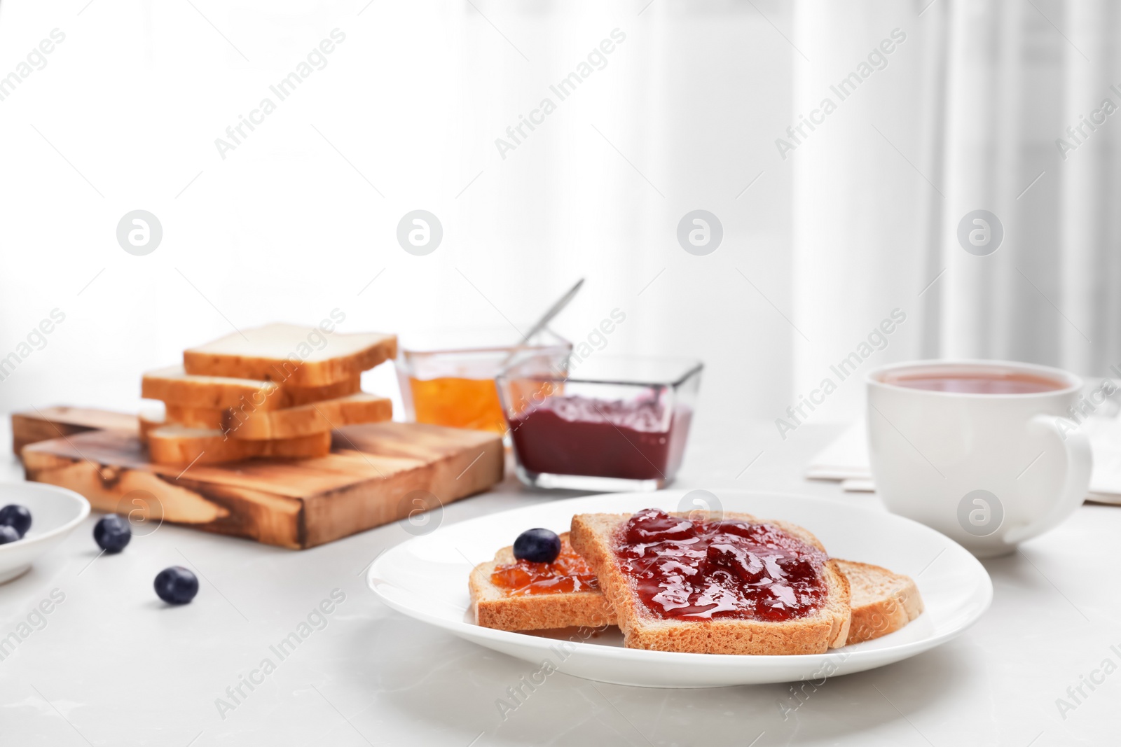 Photo of Toasts with jam and cup of tea on table